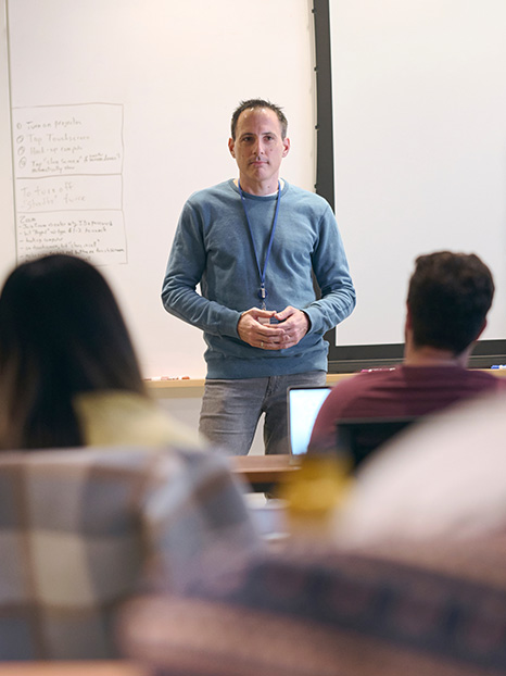 A professor stands in front of a classroom of residents, fellows, and PhD candidates. 