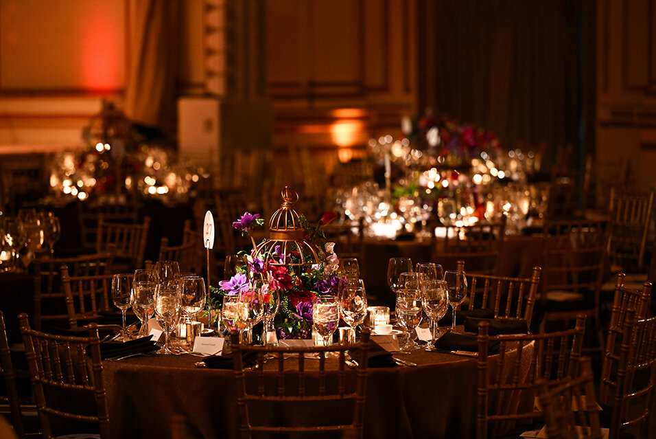 A candlelit Fall Party table decorated with a floral centerpiece.