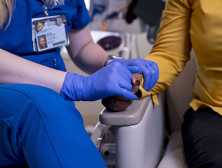 An MSK nurse holds a patient’s hand.