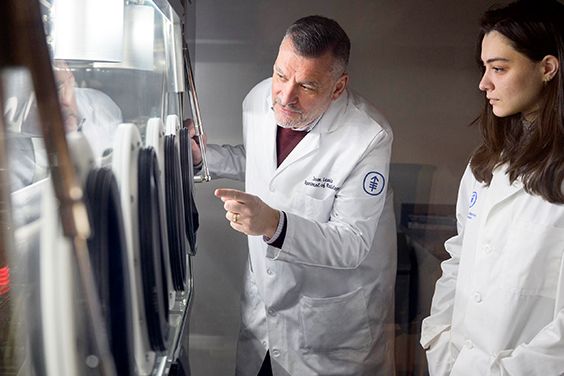 MSK scientists in lab coats examining equipment.